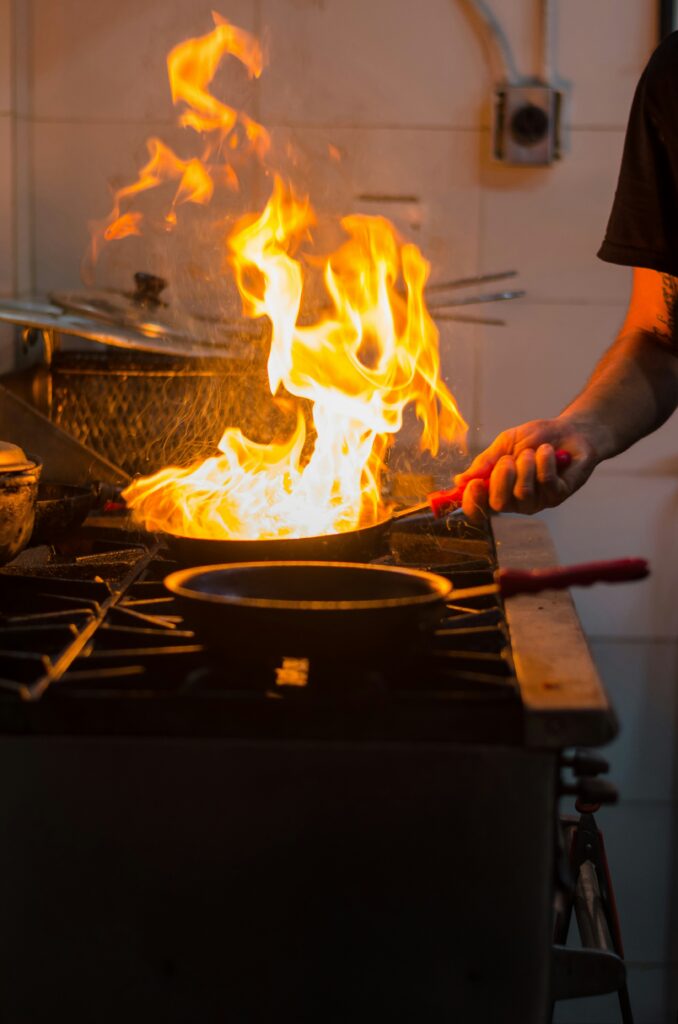 Cook tossing food in a pan over a high gas flame